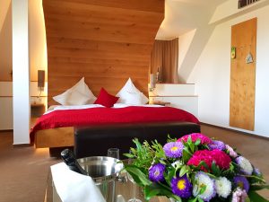 Doppelbett in Holzfassoptik mit einem Sektempfang und frischen Blumen im Hotel zur Malzmühle