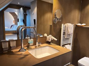 Modernes, helles Badezimmer mit einer großen Spiegelfront sowie einem Kölsch Zapfhahn am Waschbecken